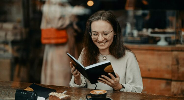 a woman sitting at a table reading a book