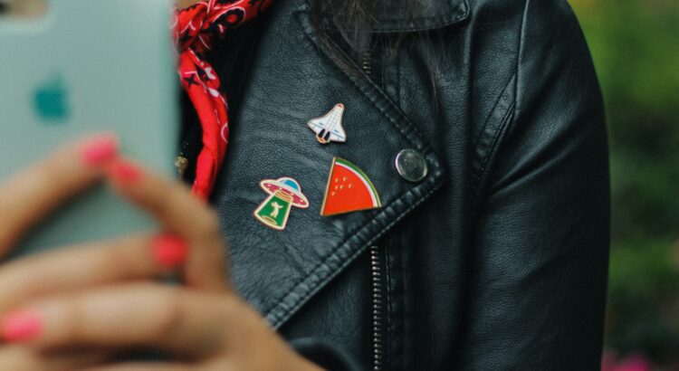 person wearing black leather jacket holding mobile phone