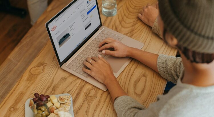 Person sitting on a table clicking on their Surface laptop